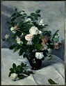 A vase of roses on a table covered with white cloth, in front of another draped white cloth.