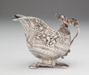 A silver tureen covered in carved flowers, shell texture, and snakes.  