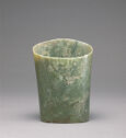 Mottled green jade object in conical form, with carved arcs design.