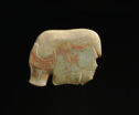 A flat jade sculpture that is round in shape and pale green in color. The bottom has engraved lines to show a rear hooved leg and a kneeled front hooved leg. The left side has square engravings to show the profile of a horn.