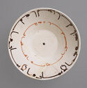 White bowl with rings of orange and black text