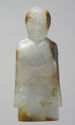 A jade pendant of a standing person that is pale green and brown in color and has been carved with fine lines to outline a wrapped robe, belt, draped sleeves, their face, and short hair. The head is large and round.