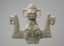 Carved jade sculpture of a stylized central human figure and mask framed by two birds.