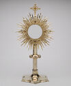 An object which looks like the rays of the sun and a cross on a wide fluted base. 