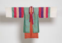 A wide silk robe hung with its sleeves straight out. The coat’s body is teal and orange underneath with a white and hot pink collar. The long sleeves have thick stripes in white, teal, hot pink, pale pink, purple, and hot pink again.
