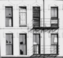 A black and white photograph of a white building with windows and two metal platforms.