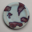 A circular dish shown from above. It is pale blue with large, dark purple splotches.
