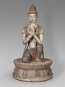 This is a statue of a person, with their hands clasped infront of them, kneeling on a circular platform on one knee.
