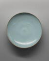 A circular dish shown from above. It is pale blue with an off-white rim.