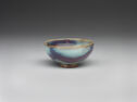 A small pale teal bowl with large spots of purple glaze.