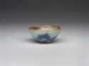 A small pale teal bowl with spots of purple glaze.