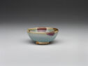 A small, wide pale teal bowl with spots of purple glaze. 