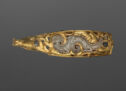 Horizonal small gold buckle object with a stylized jade dragon inlaid into the center.　