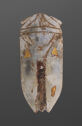 A jade sculpture of an oblong cicada. The top is curved with carved lines to detail the head. The middle and bottom are shaped into two longer points with three gold shapes on them. It is light grey in color with brown coloration in the engraved parts.