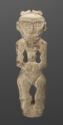 A pale jade statuette of a standing female figure with a small body and a large head. The space in between the legs and arms are cut out. There are engraved lines on the figure to show fingers and details of the face.