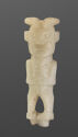 A pale jade statuette of a standing female figure with a small body and a large head. The space in between the legs is cut out. There are engraved lines throughout the piece that show details in the fingers, body, and face. The face has a large mouth, rou