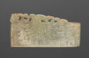 A jade piece that is shaped into a rectangle and shown horizontally. It is pale green in color. There are many swirling relief lines through the piece that create a pattern. Along the top of the piece is the shape of a long, thin dragon with a detailed he