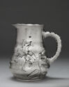 A silver pitcher covered in a hammered pattern and a large lily engraving