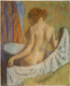 A nude woman standing at a bath tub and holding a towel