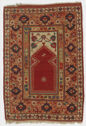A rectangular carpet with a thick orange border that has a dark green, red, and white geometric floral pattern. At the center is a smaller rectangle space that has a large red shape that is rectangle at the bottom and comes to a diamond shape at the top. It is detailed with a white border and above it is a simple geometric floral motif in green and red with a white background.