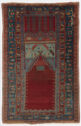 A rectangular carpet with a large, dark blue border with yellow, red, and blue geometric floral details. At the bottom center is a solid red pentagon that points up. Above it shows geometric details on a light blue background and a red and blue pattern above it. The red and blue pattern have two large arrows that point down.