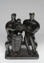 
A sculpture of a family of three—mother, father, and child—sitting together on a bench. 