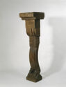 A carved, columnar wooden sculpture on a small square base, and a wider flat top.