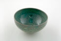 A gray green bowl with a short, narrow base, decorated with cranes and other designs