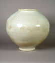 An off-white porcelain vase that has a round body, a small flat foot, and a short flat top lip. The middle to bottom of the piece is mottled with a darker off-white brown color.