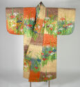 A wide silk robe hung with its sleeves straight out. The coat is patterned with large checkered squares that are tan, blue, purple, orange. There is also a thin, golden geometric pattern all over. Large embroidered flowers and leaves go across the sleeves and along the bottom hem.