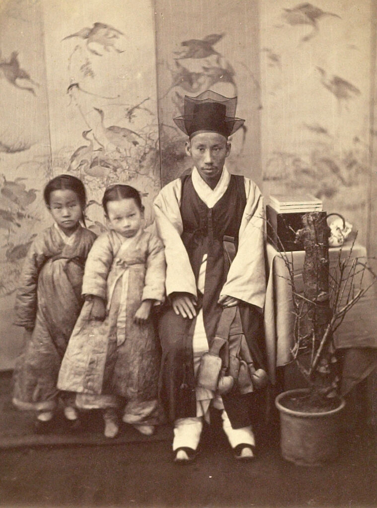 Seated Young Korean Man And Two Small Girls