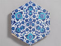 A hexagonal tile decorated with repeating blue floral designs.