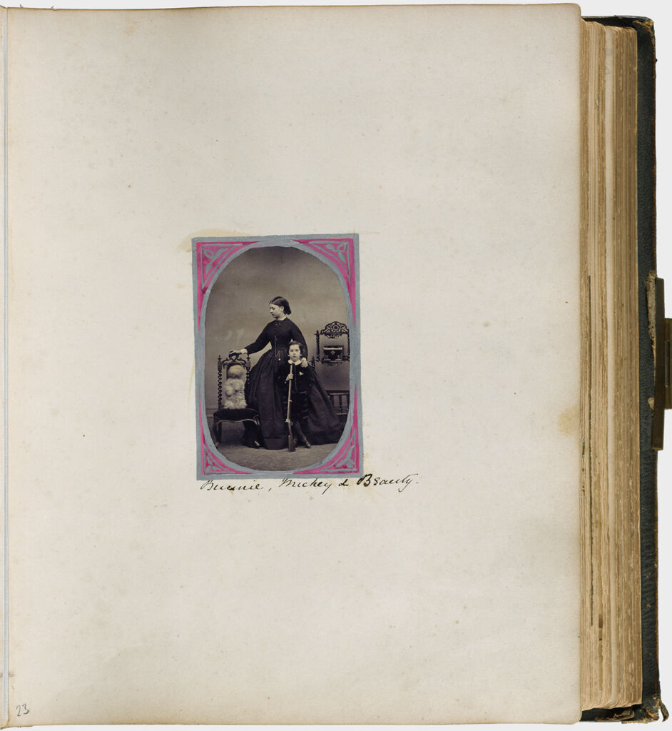 Untitled (Single Photograph Labeled Bunny, Mickie And Beauty, Woman Standing In Center Of Photograph, Left Hand On Shoulder Of Boy Holding Rifle, Dog Sitting Up In Chair To Left)