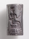 An intaglio hematite object in the shape of a cylinder. It is engraved with an image of a seated man with an arm bent up in front of him. He has a beard and is wearing a long skirt. There is an engraved circle with a star in it next to him.