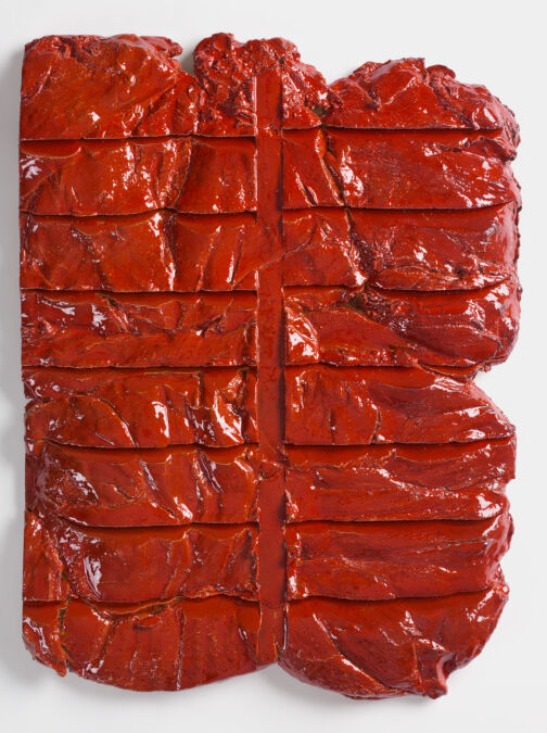 
A bright red, rectangular ceramic relief with horizontal and vertical impressions on the surface.