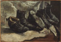 Still life of three pairs of worn black shoes sitting diagonally in a row on a white cloth.