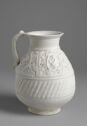 A white ceramic vessel with a round body and a smaller top opening. On the body is a pattern of slanted lines and a floral pattern with tiny holes in it.