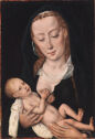A woman holds a baby, who touches her right breast.