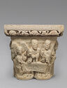 Stone capital with figures. The abacus of the capital is a wide, rectangular stone slab carved with text and foliage.