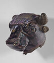 A dark metal head of a cow or bull with short horns and fine detail in the face.