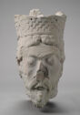 Gray stone head of man with curly hair and crown