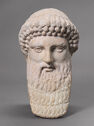 A marble sculpture depicts the head of a man with a long beard and rows of curls above the forehead.