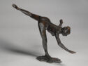 Bronze sculpture of a woman in a ballet pose, arms splayed as her left leg points higher up into the air.