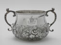 A two-handled cup decorated with cherubs and flowers.