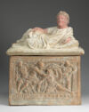 A small box-like terracotta container embellished with figures in relief