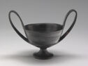 A wide cup with large handles on either side and a low foot.