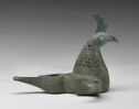 A metal bird with incised designs, a well in the body, and openings in the wings and tail