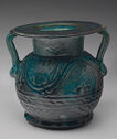 Opaque blue-green glazed faience amphora with two handles, short neck, wide flat lip, and etched pattern decorations.