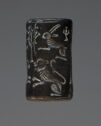 An intaglio black, hematite object in the shape of a cylinder. It is engraved with an image of a rabbit on the top and a lion on the bottom. Both of their front legs are raised.