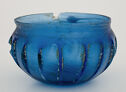 Translucent cobalt blue glass bowl with chipped rim, short concave shoulder, and convex ribbed sides showing staining or dirt accretions